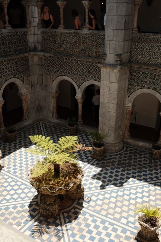 Tiled courtyard with arched colonnade and a potted fern
