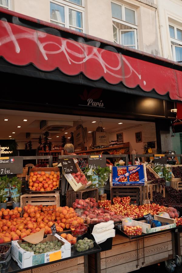 Market stall piled with fruit under a red awning