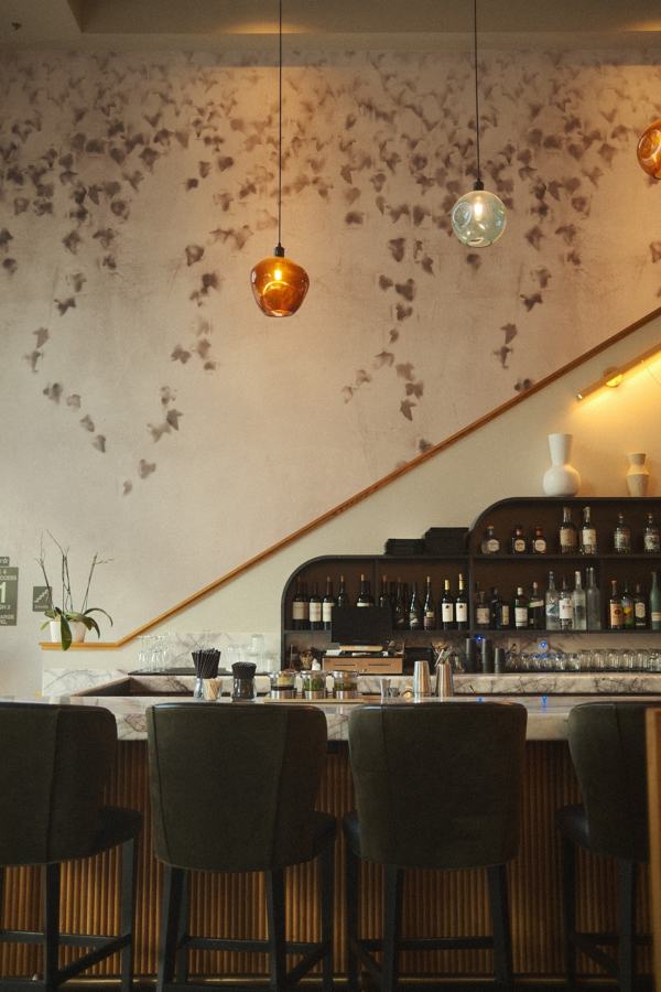 Bar with leaf-patterned wall and pendant lights by the staircase